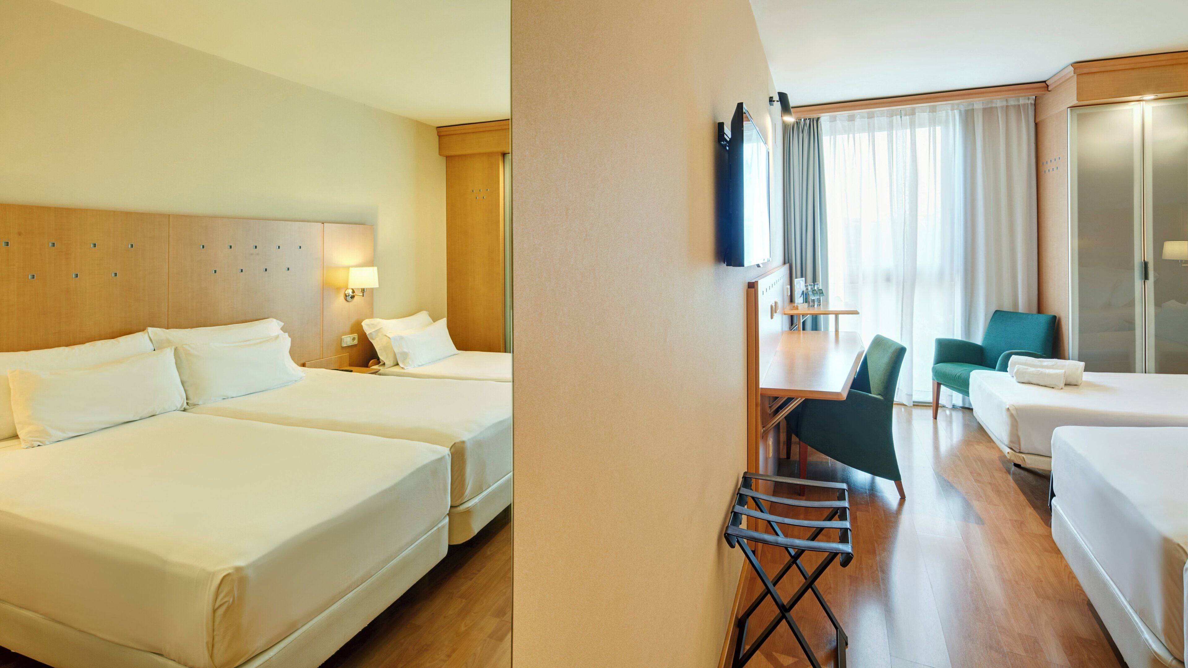 Ein Hotelzimmer mit zwei Betten, einem Schreibtisch, einem Stuhl und einem Fernseher.