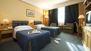 Een hotelkamer met twee bedden, een bureau, een televisie en een stoel.