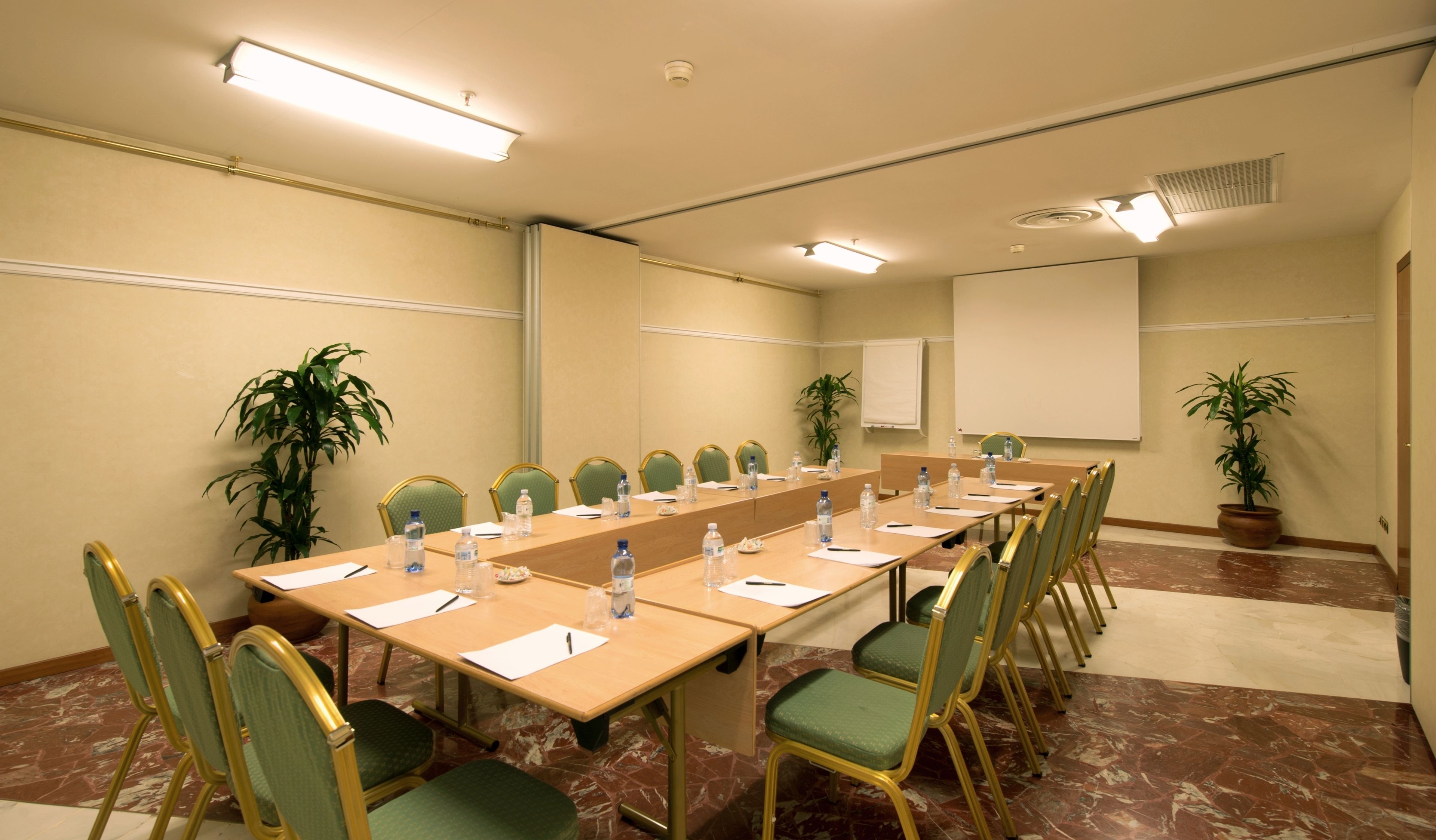 A conference room with a long table, chairs, water bottles, and a whiteboard.