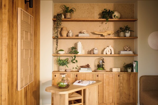 Un mueble de madera con estantes que contienen libros, objetos decorativos e plantas.