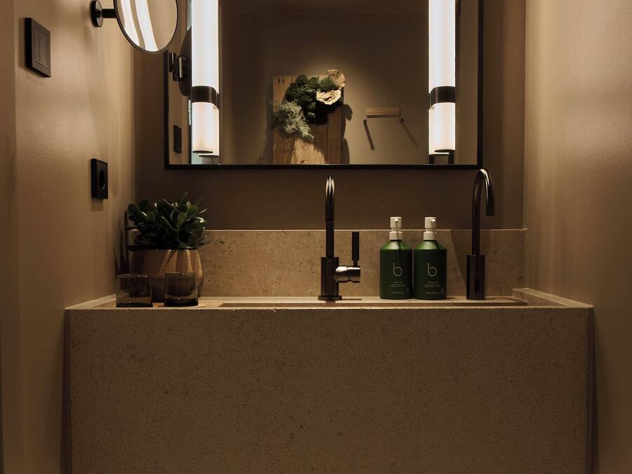 Un baño con un espejo grande, un lavabo y un estante con toallas dobladas.