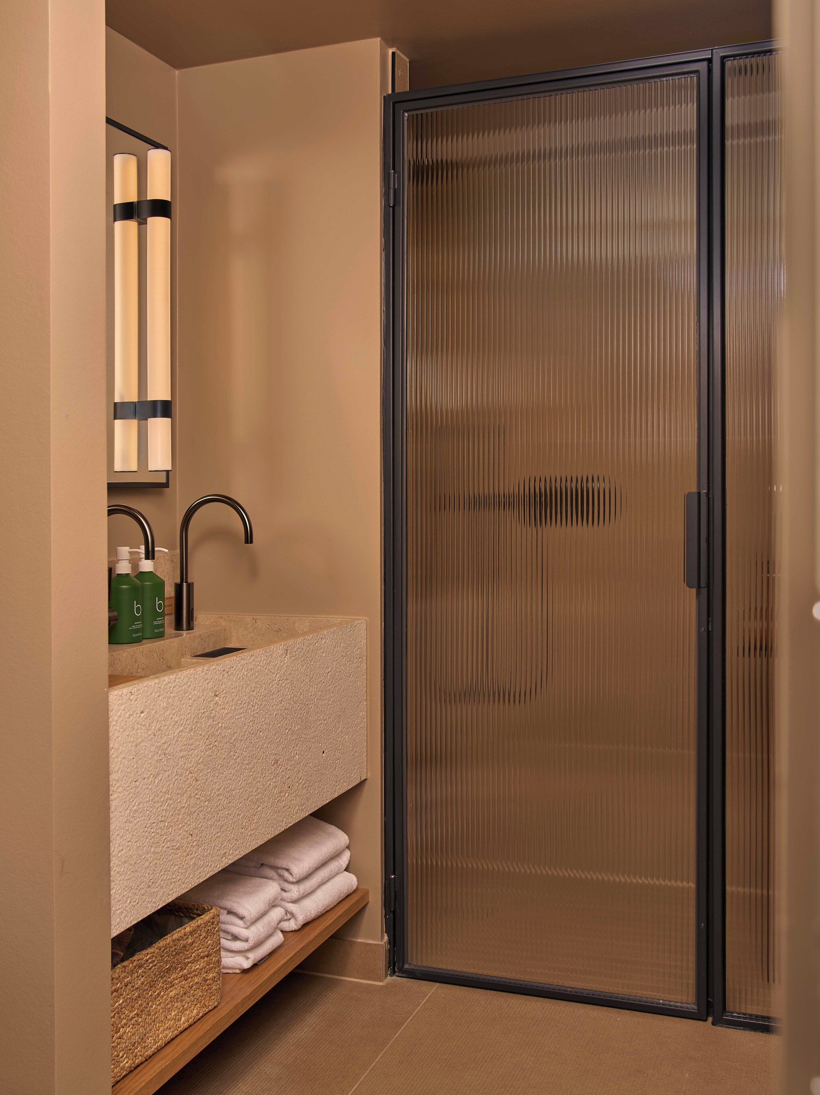 Une salle de bain moderne avec une douche à parois de verre, un lavabo avec un porte-serviettes et un miroir.