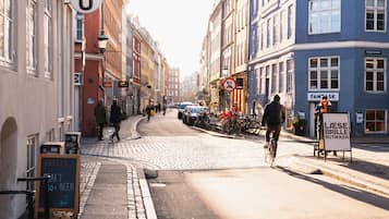A cobblestone street lined with historic buildings, a cyclist, and a signboard.