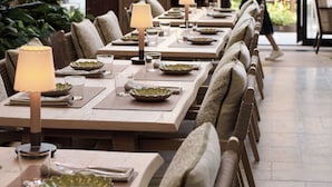 A restaurant with long wooden tables, cushioned chairs, and hanging pendant lights. - 1 Hotel Copenhagen (Copenhagen)
