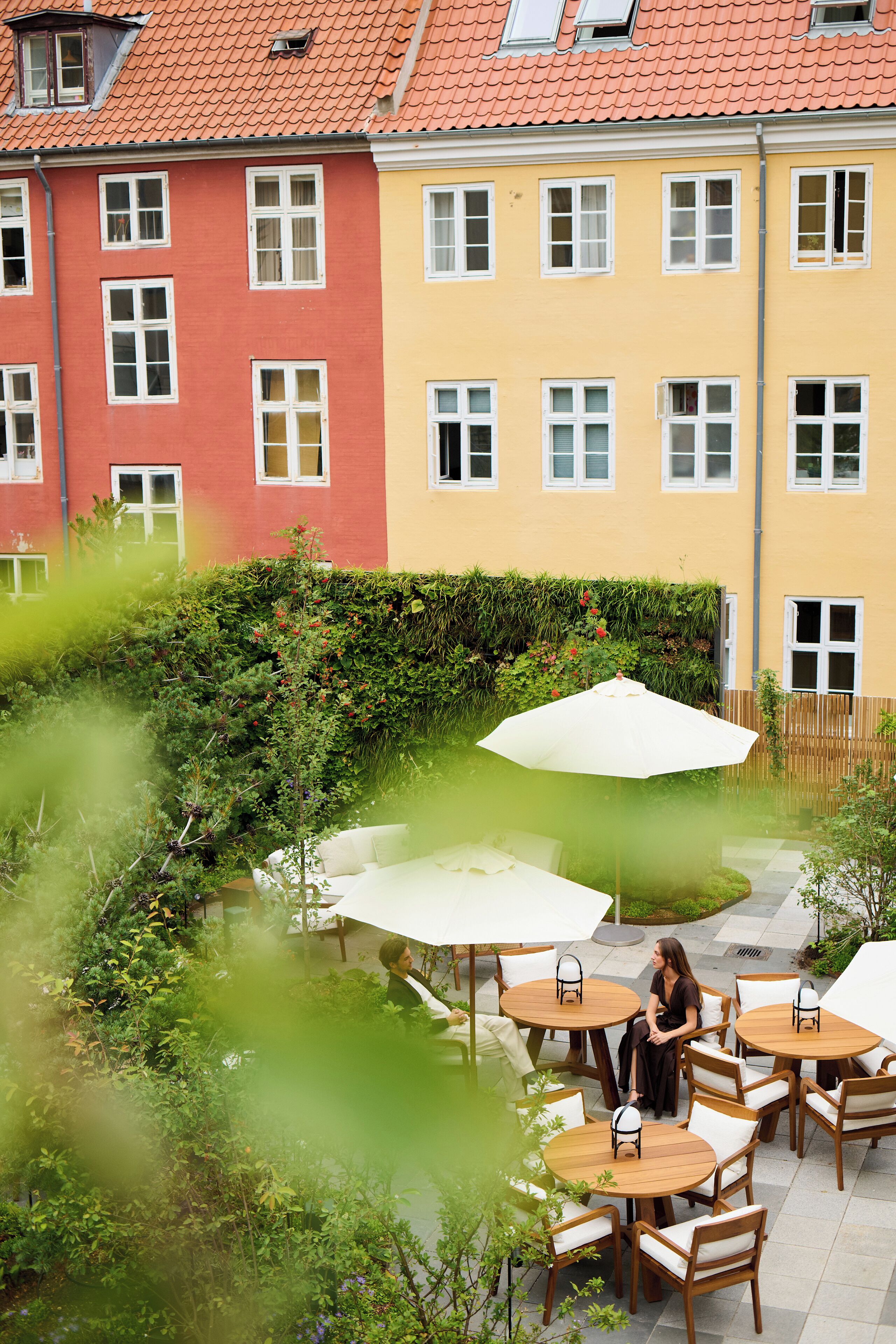 A courtyard with outdoor seating and a person sitting at a table.