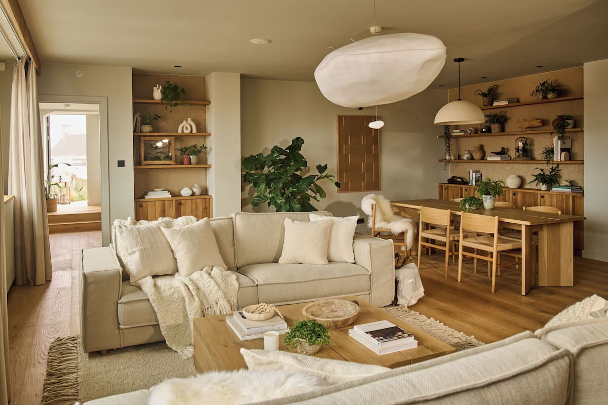 A cozy living room with a beige sofa, wooden coffee table, and a dining area with a wooden table and chairs.