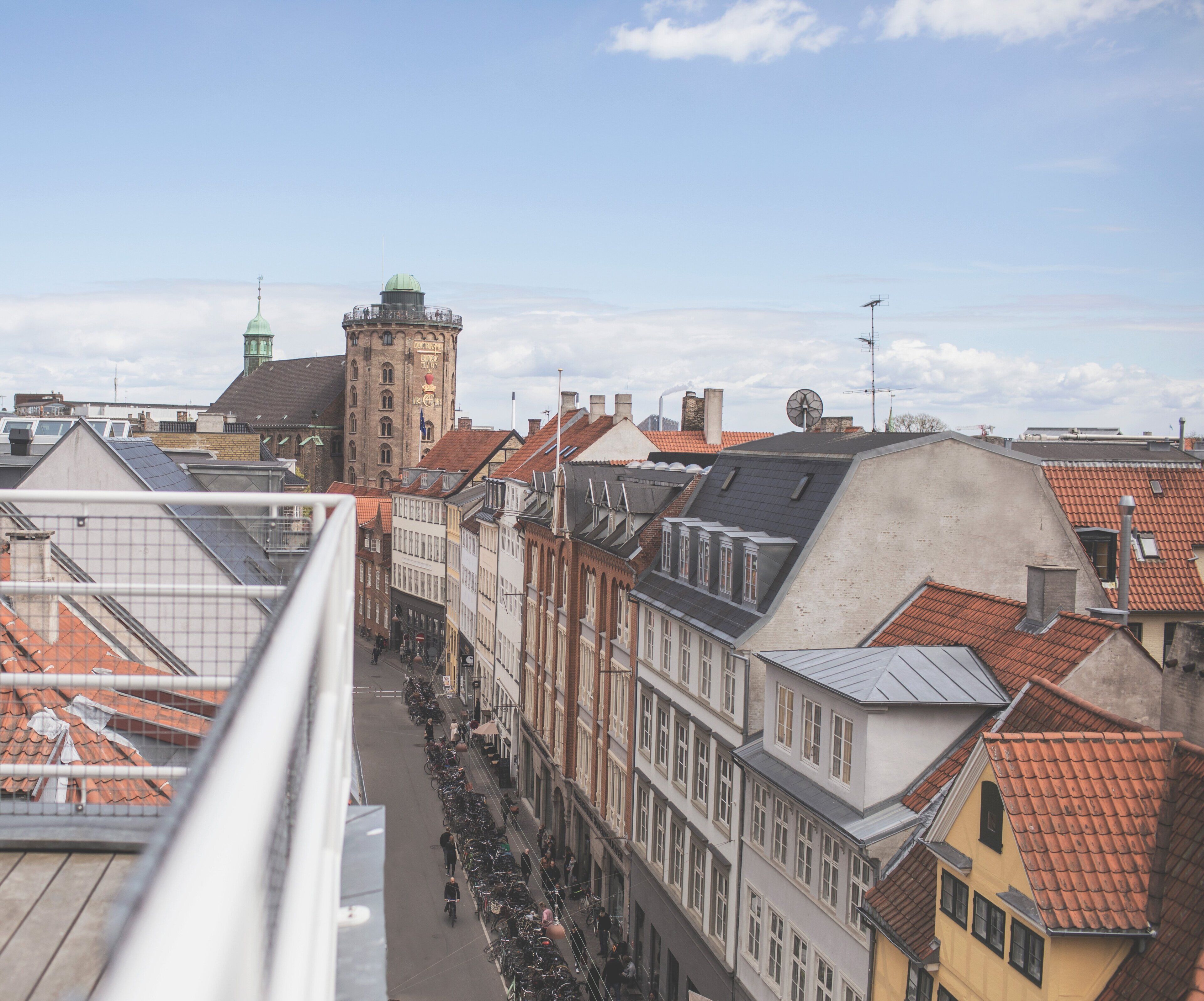 Vista de una calle con edificios históricos, una torre y un puente.