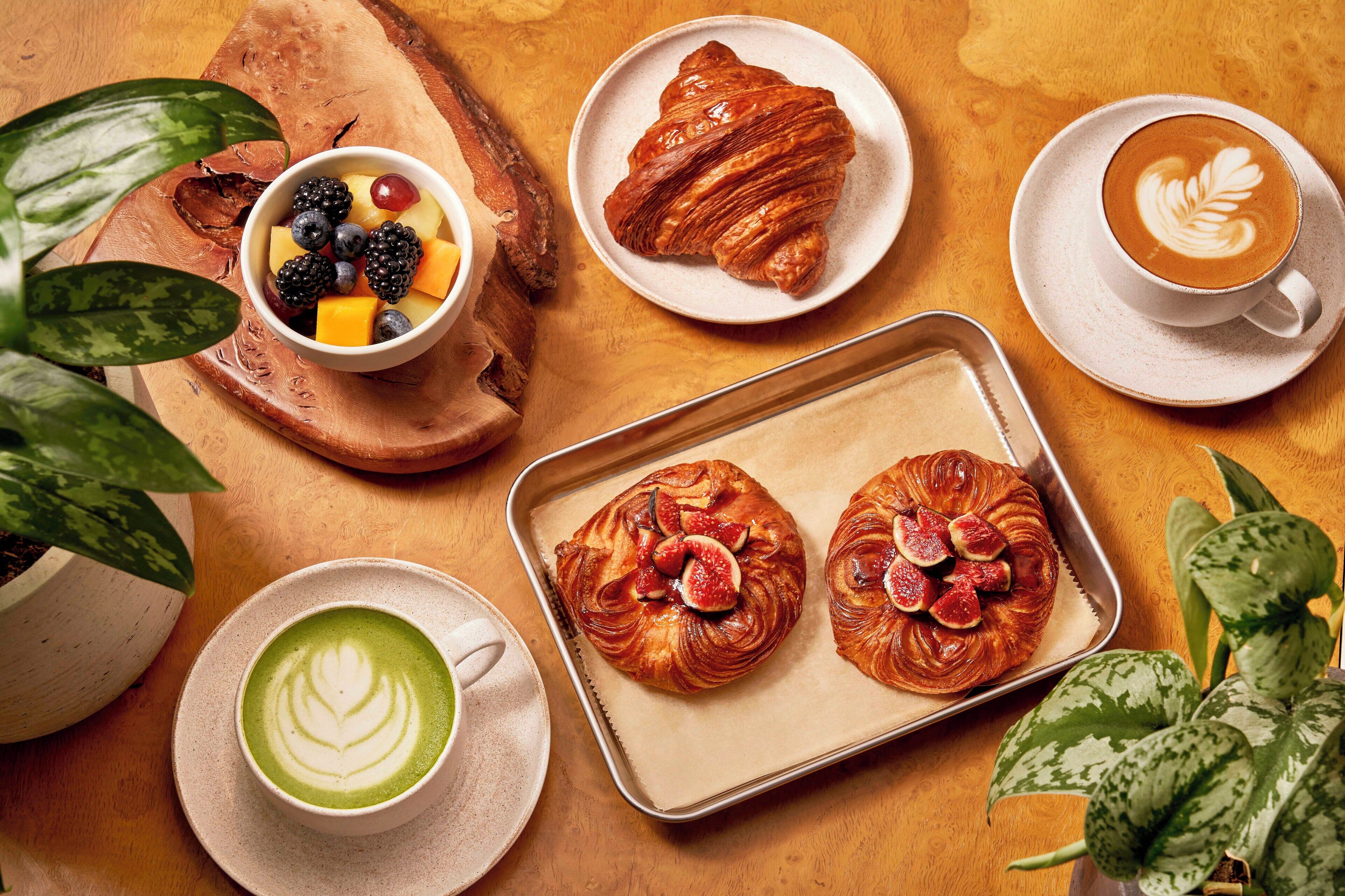 Un desayuno con croissants, fruta y café.