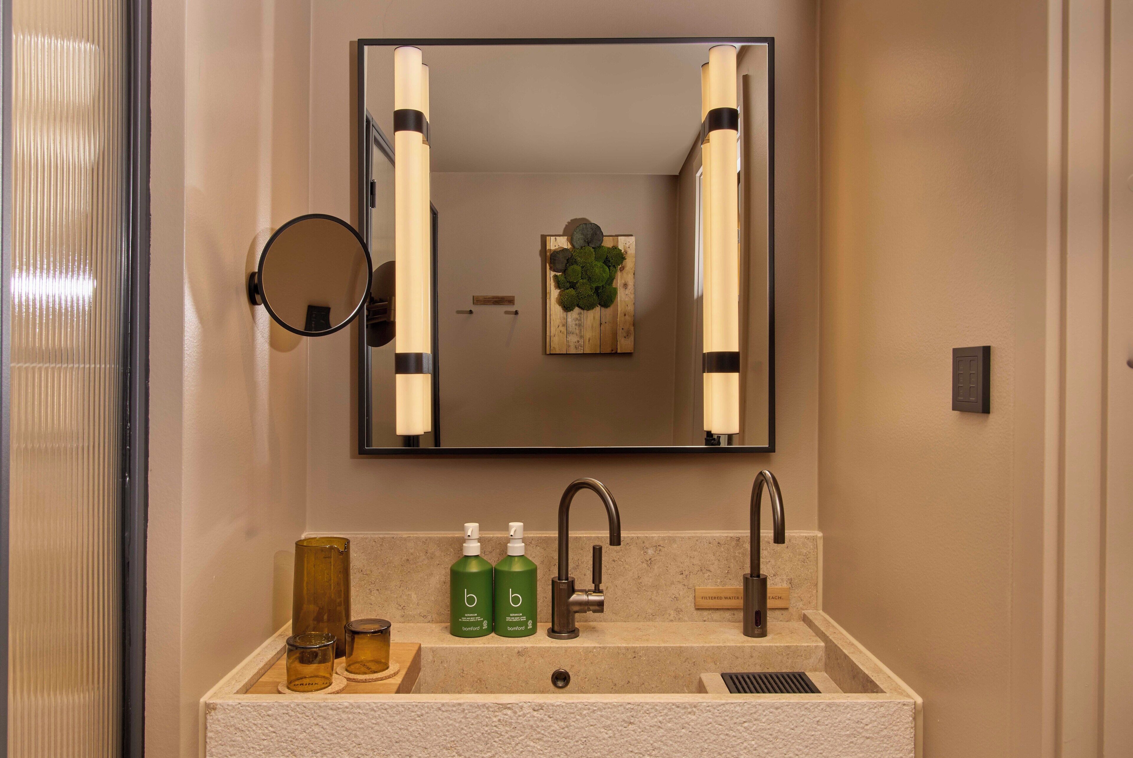 A bathroom with a large mirror, two sinks, and a towel rack.