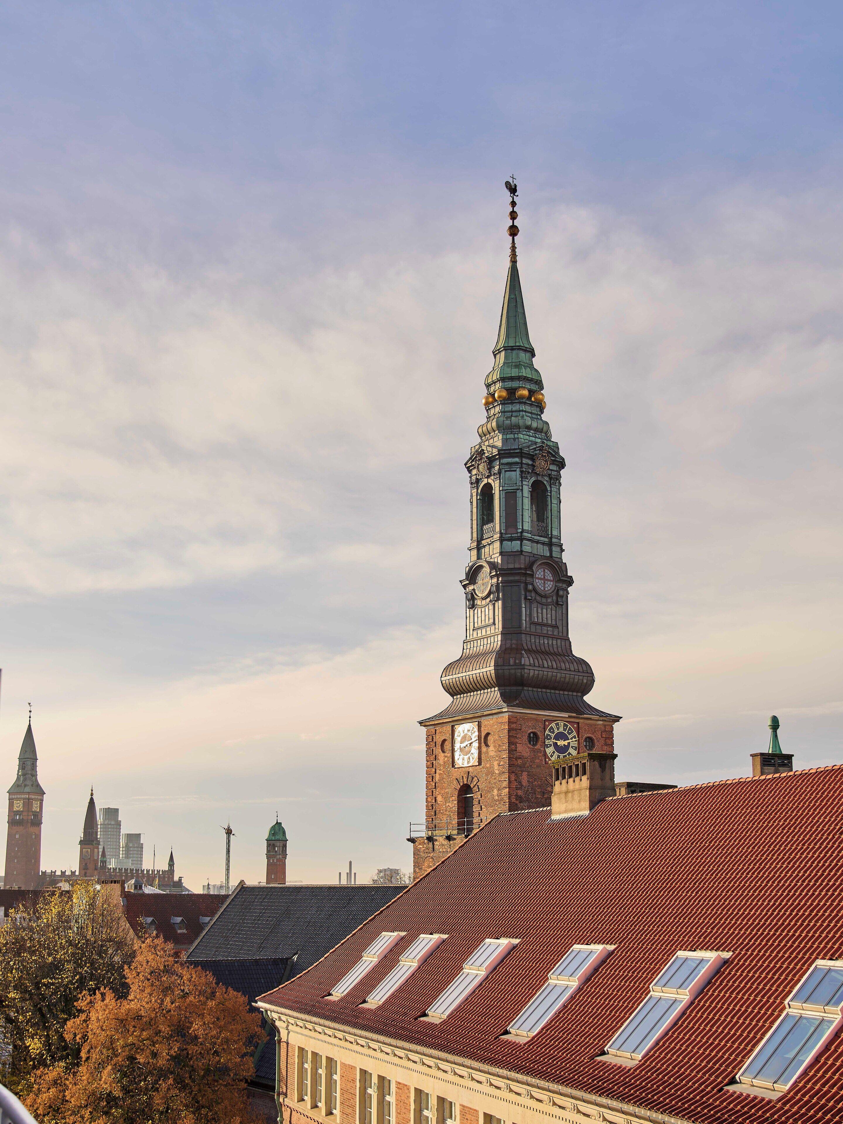 Ein historisches Gebäude mit einem markanten Turm, der eine Uhr und eine Turmspitze zeigt.