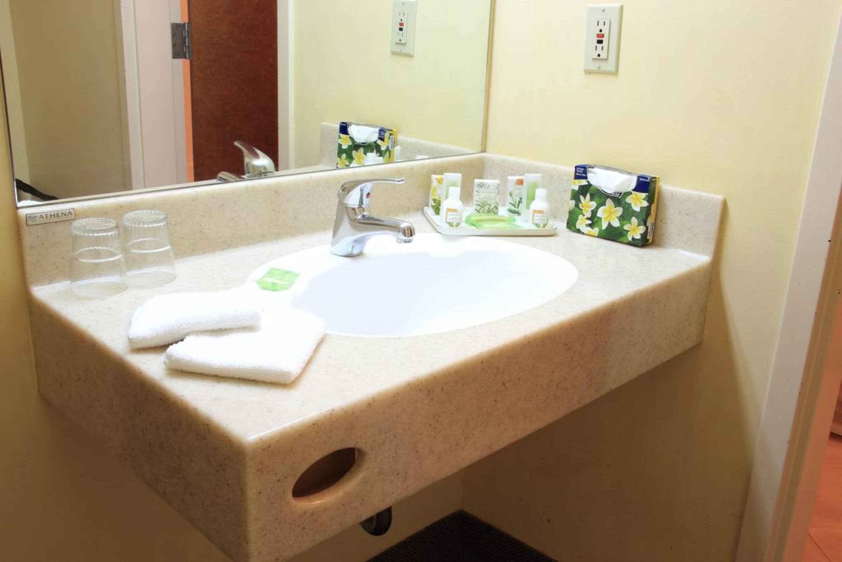 A hotel bathroom with a sink, mirror, and toiletries.
