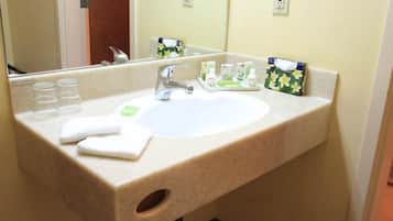 A hotel bathroom with a sink, mirror, and toiletries.