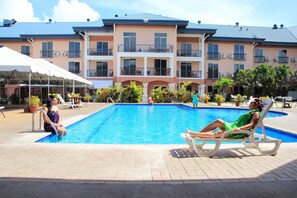 A swimming pool area with lounge chairs and a covered seating area.