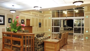 A lobby with a reception desk, seating area, and a glass door leading outside. - Tradewinds Hotel (Ottoville)