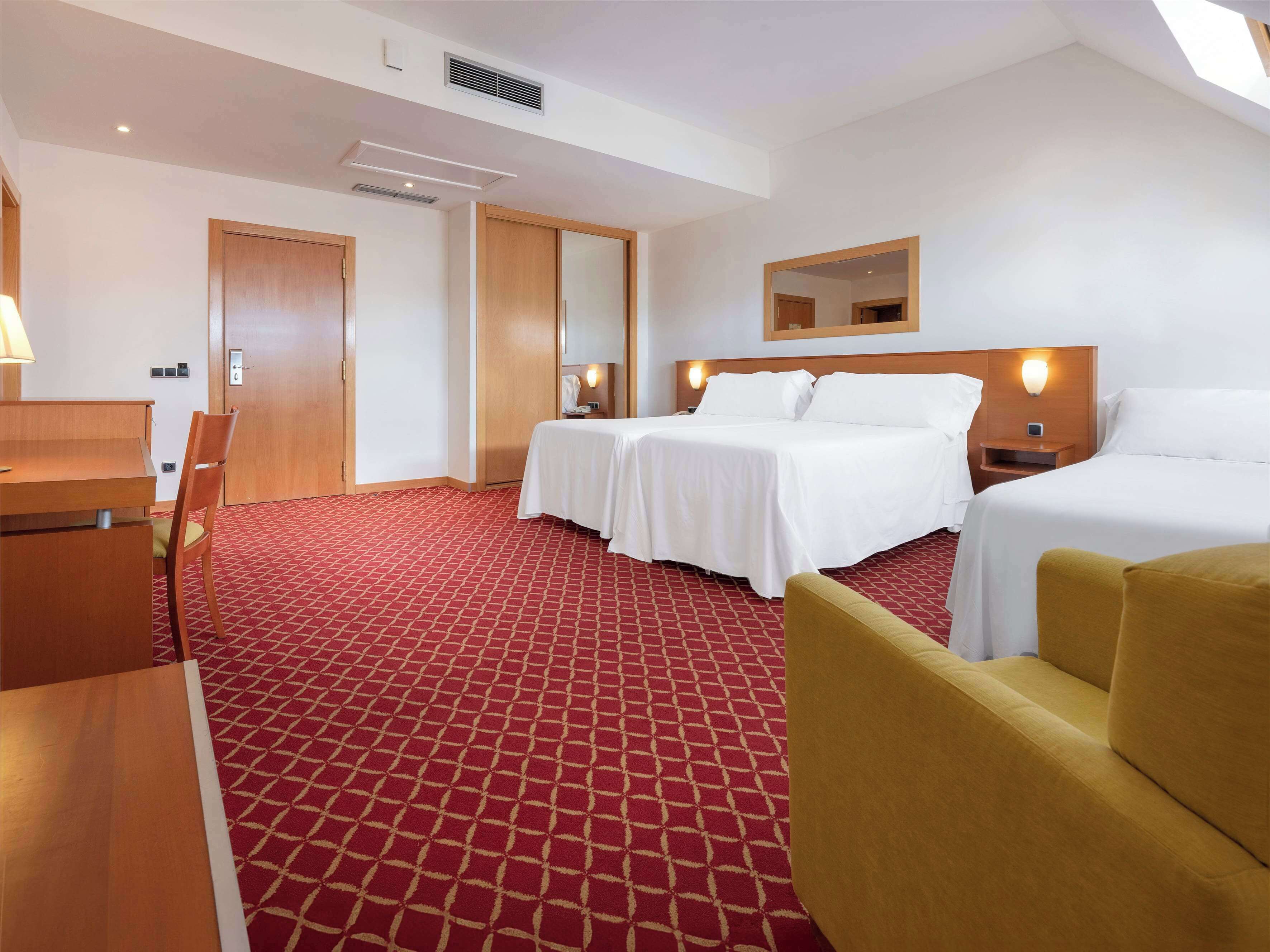 Una habitación de hotel con cama, escritorio, silla y un pequeño sofá.