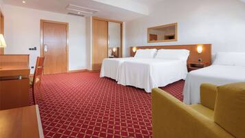 Una habitación de hotel con cama, escritorio, silla y un pequeño sofá.