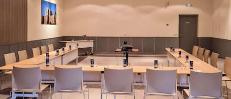 Una sala de conferencias con una larga mesa, sillas, un atril y un proyector.
