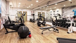 A gym with various exercise equipment, including treadmills, weight machines, and free weights.