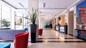 A modern lobby with a reception desk, seating area, and a large plant.