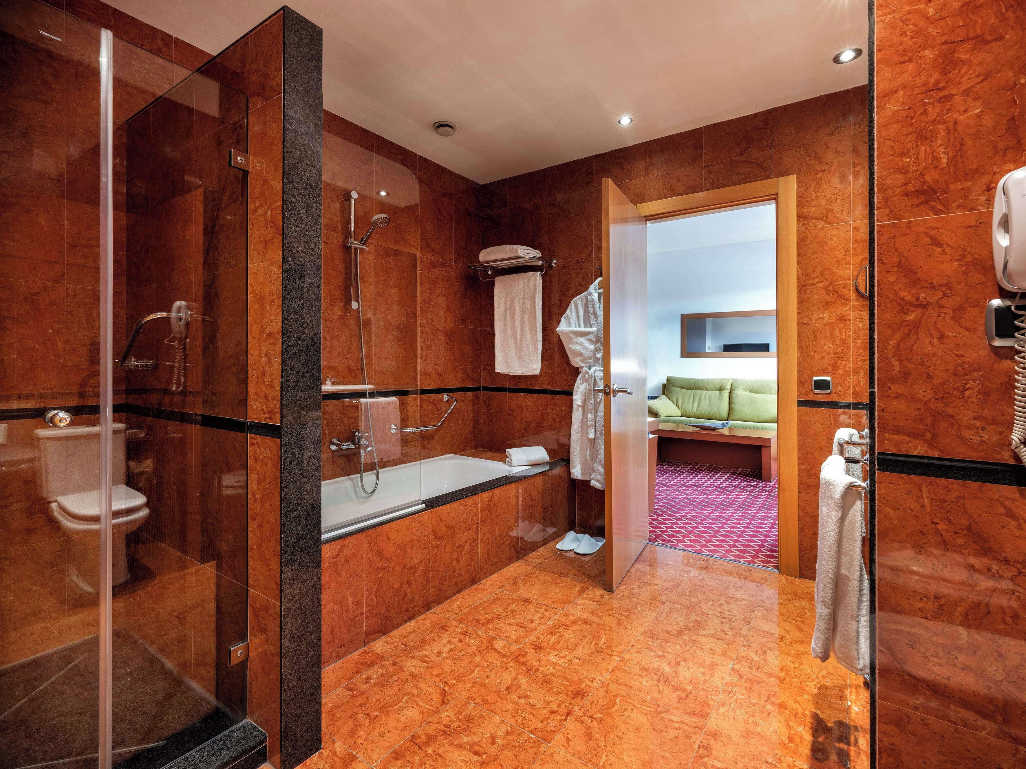 Une salle de bain moderne dotée d’une douche à parois de verre, d’une baignoire et de toilettes.