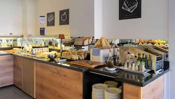 Mostrador de buffet con diversos alimentos, como pan, pasteles y salsas.
