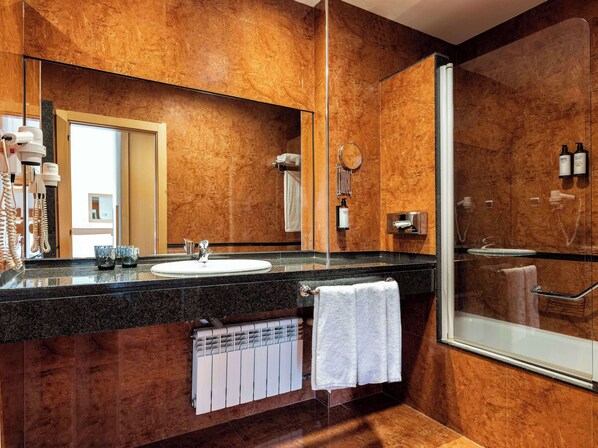 A modern bathroom with a large mirror, a sink, a glass shower enclosure, and a towel rack.