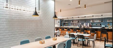 A modern restaurant with a brick wall, wooden tables, and blue chairs.