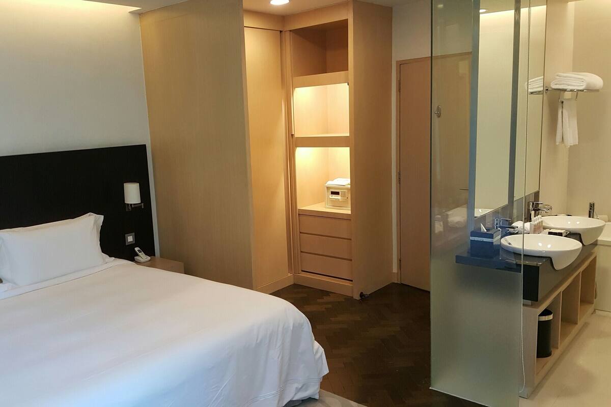 A hotel room with a bed, a walk-in closet, and a bathroom with a sink and mirror.