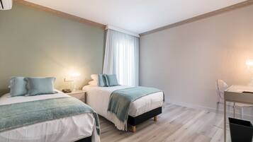 A bedroom with two beds, a desk, and a chair.