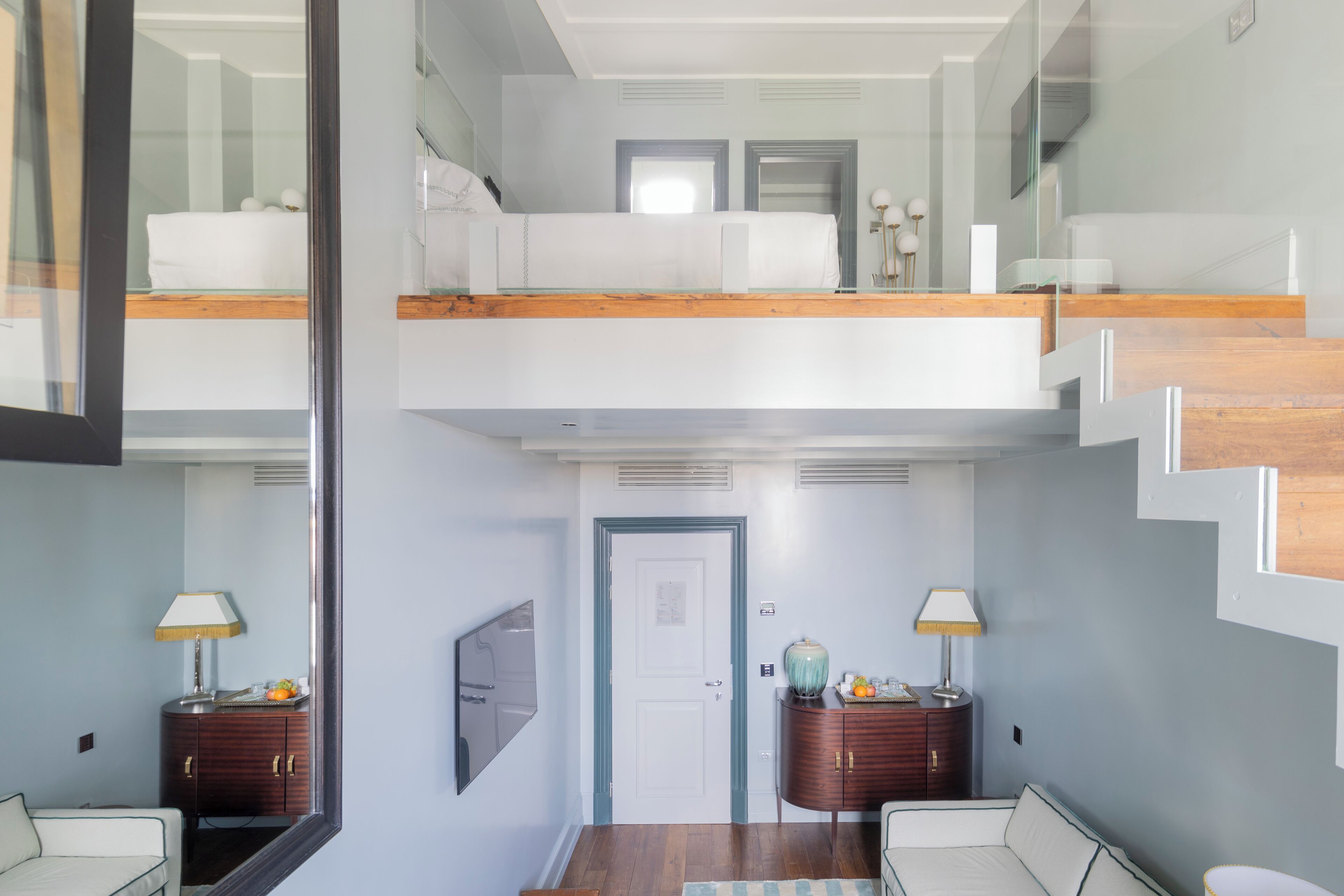 Un interior moderno con una escalera, una cama, un escritorio y un espejo.