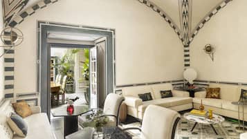 Cozy living space with a high ceiling, sofa, armchairs, and dining area.