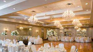 A banquet hall with round tables, white tablecloths, and chairs with white sashes. - Baymont by Wyndham Pompton Plains/Wayne (Pompton Plains)