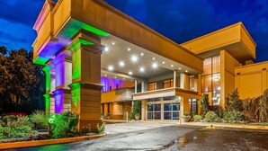 A modern hotel with a two-story structure, large windows, and a well-lit entrance. - Baymont by Wyndham Pompton Plains/Wayne (Pompton Plains)