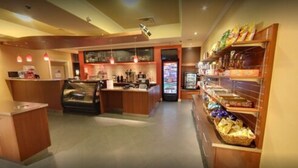 A bakery with a display counter, a seating area, and shelves stocked with baked goods. - Days Inn & Suites by Wyndham Niagara Falls Centre St. By the Falls (Niagara Falls)