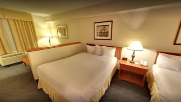 A hotel room with two beds, a bedside table with a lamp, a framed picture on the wall, and a window with curtains.