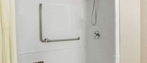 A white bathtub with a handheld showerhead and a grab bar.