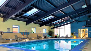 An indoor swimming pool with clear blue water, surrounded by lounge chairs and safety signs. - Days Inn & Suites by Wyndham Niagara Falls Centre St. By the Falls (Niagara Falls)