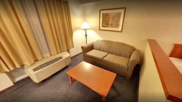 A hotel room with a sofa, a small table, a lamp, and a heater.