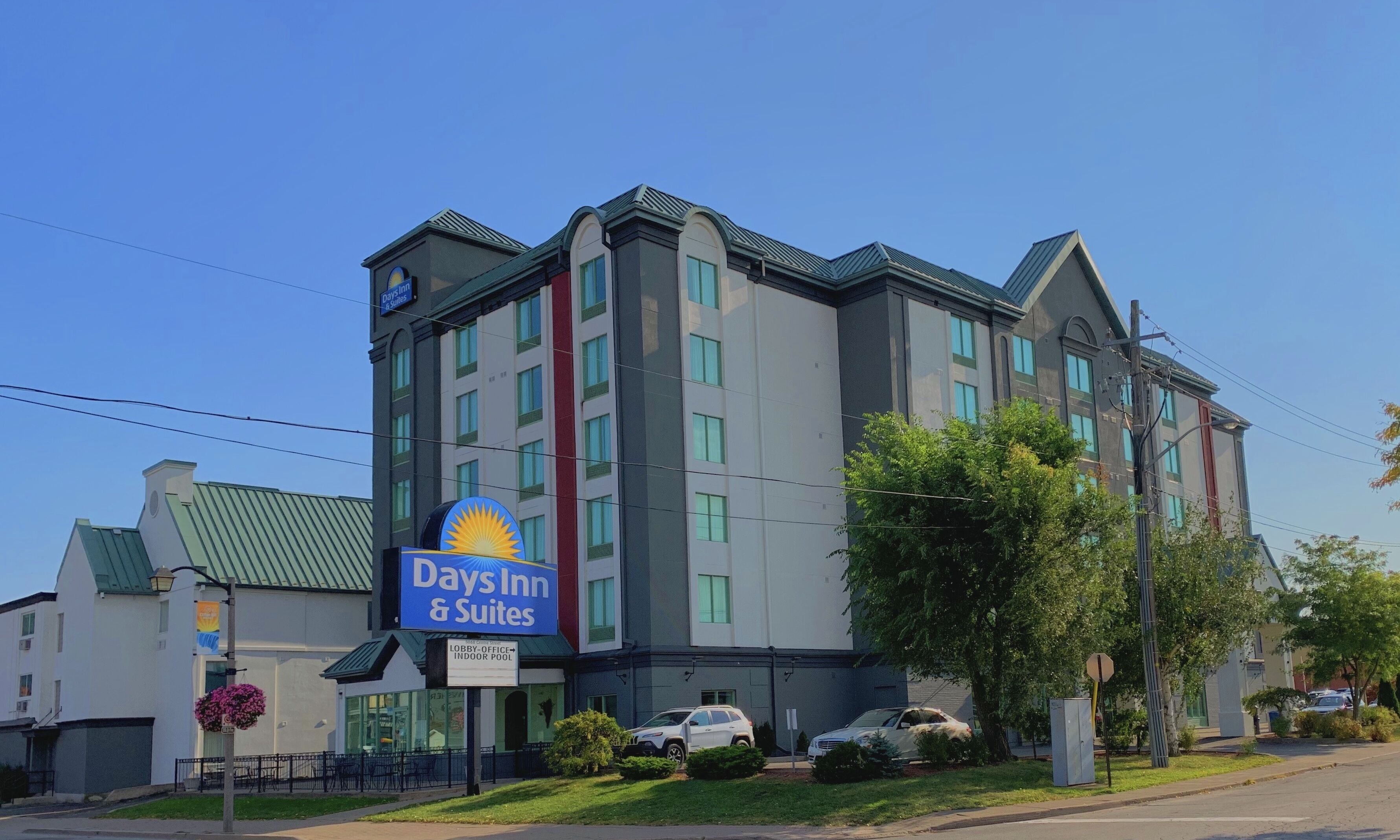 A Days Inn & Suites hotel with a modern design, featuring a prominent sign, multiple floors, and a green roof.