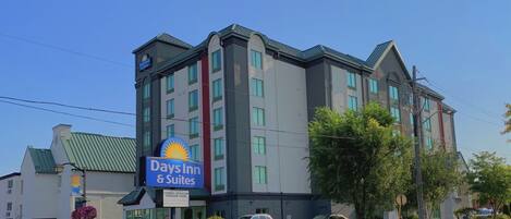 A Days Inn & Suites hotel with a modern design, featuring a prominent sign, multiple floors, and a green roof.