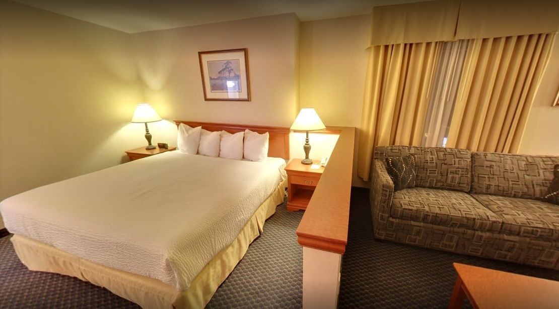 A hotel room with a large bed, two bedside lamps, a sofa, and a picture on the wall.