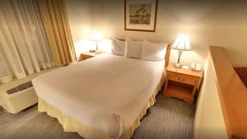 Habitació d'hotel amb un llit, dues taules de nit amb làmpades, un calefactor i una finestra amb cortines.