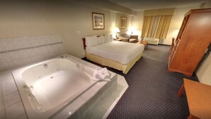 A hotel room with a large bathtub, a bed, a desk, and a wardrobe. - Days Inn & Suites by Wyndham Niagara Falls Centre St. By the Falls (Niagara Falls)