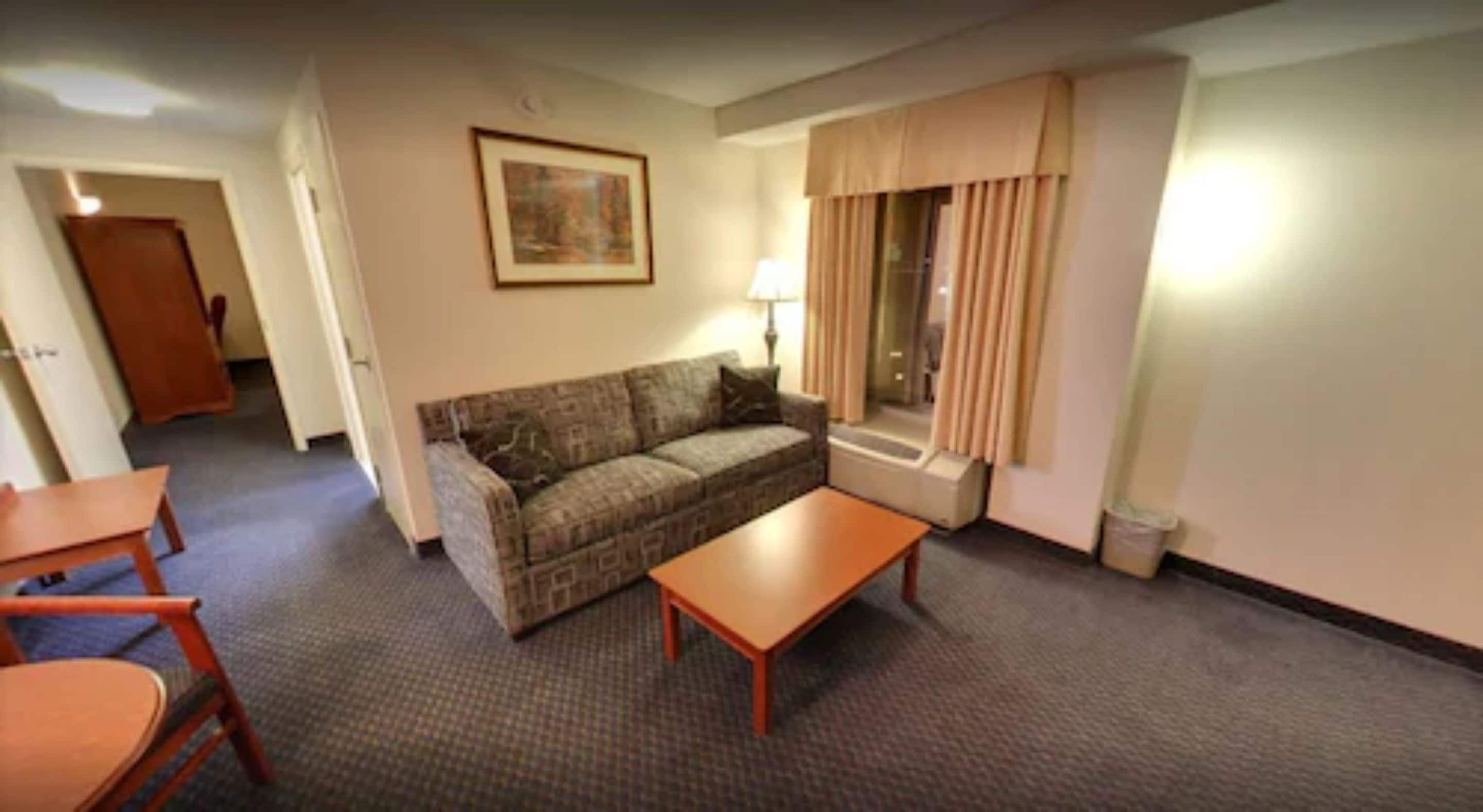 Ein möbliertes Wohnzimmer mit Sofa, einem kleinen Tisch und einer Lampe.