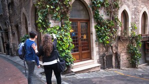 A building with a stone facade, arched windows, and a wooden door. - Hotel Fortuna (Perugia)