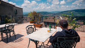 A terrace with a table, chairs, and a person reading a book. - Hotel Fortuna (Perugia)