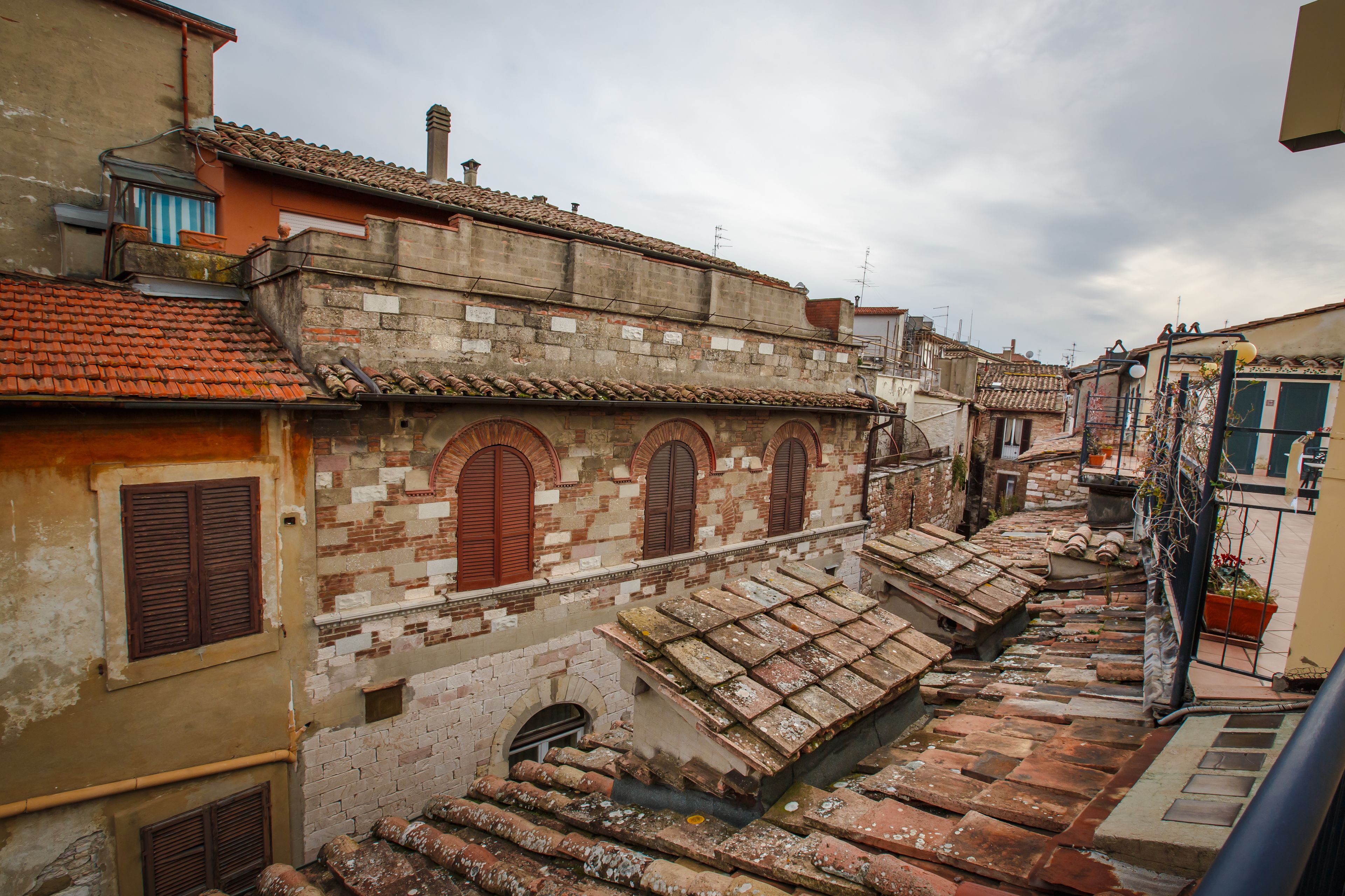 Una calle estrecha con edificios tradicionales, incluyendo un edificio con tejado de baldosas y ventanas arqueadas.