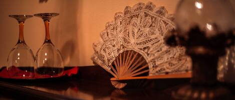 A table with two clear wine glasses, a lace fan, and a decorative vase.