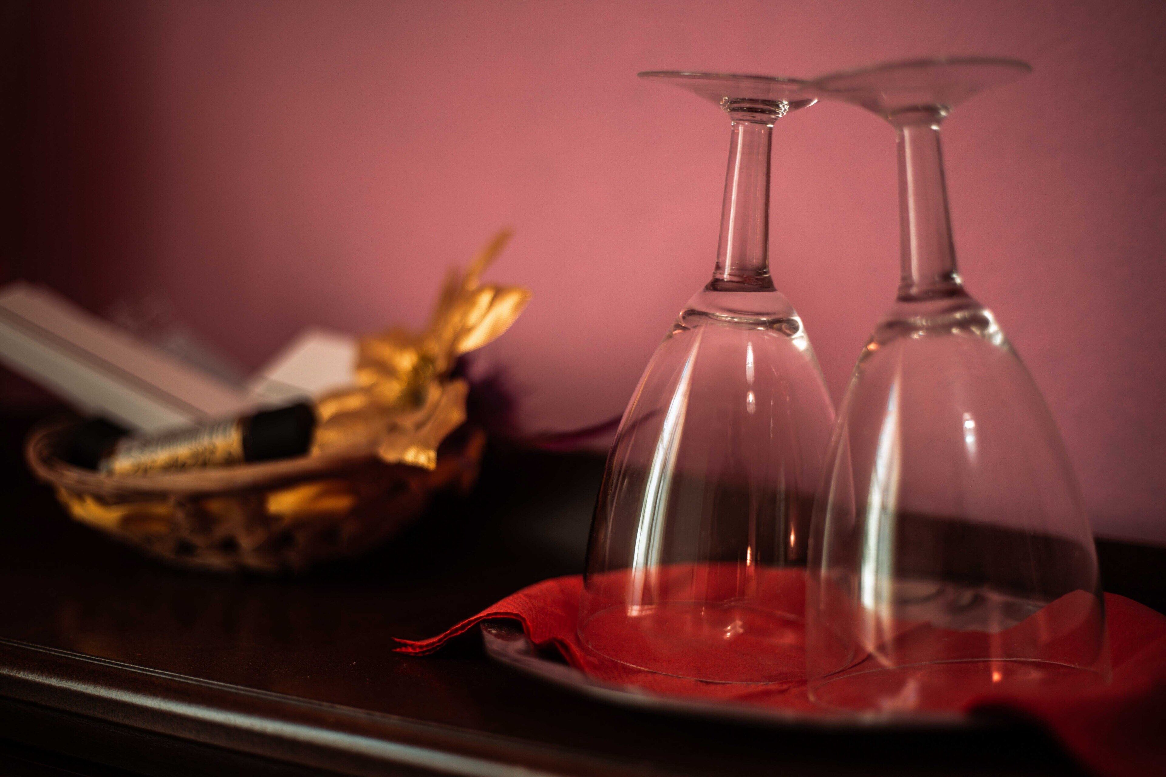 Two clear wine glasses on a red cloth with a basket in the background.