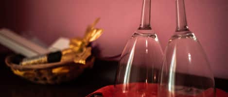 Dos copas de vino transparentes sobre un mantel rojo, con una cesta al fondo.